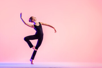 Young teenager dancer dancing on a red studio background. Ballet, dance, art, modernity, choreography concept - obrazy, fototapety, plakaty