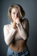 Girl, blonde hair in a beige top and blue jeans, romantic portrait.