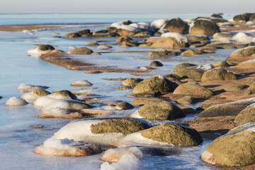 Fototapeta na wymiar Winter landscape with ice and stones on frozen Sea. Ice frozen on a stone. Sea shore in winter, covered with ice and snow
