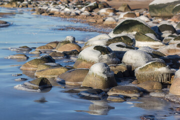 Winter landscape with ice and stones on frozen Sea. Ice frozen on a stone. Sea shore in winter, covered with ice and snow