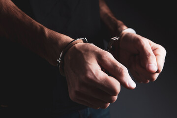 a young man in a shirt stands in handcuffs