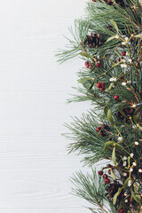 Fototapeta premium Christmas tree border with festive lights and mistletoe on white background with space for text, Christmas banner concept with copy space near fir tree branch and mistletoe