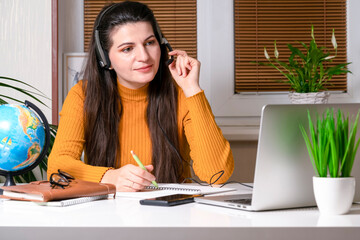 Teenage girl with headphones having online school class at home