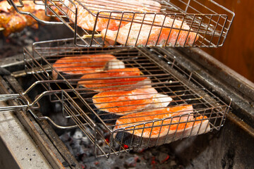 Grilled fish steaks on fire. Charcoal cooking of salmon steaks, pieces of fish on wooden grill...