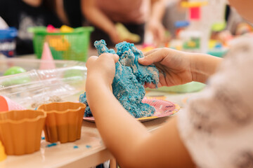 kinetic sand. children's hands play with multi-colored polymer sand.