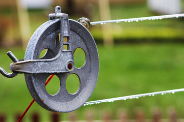 Close-up of a clothesline pulley, drops of rainwater on clothesline.