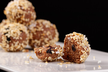 Beautiful candies with sesame seeds on a white plate on a black background