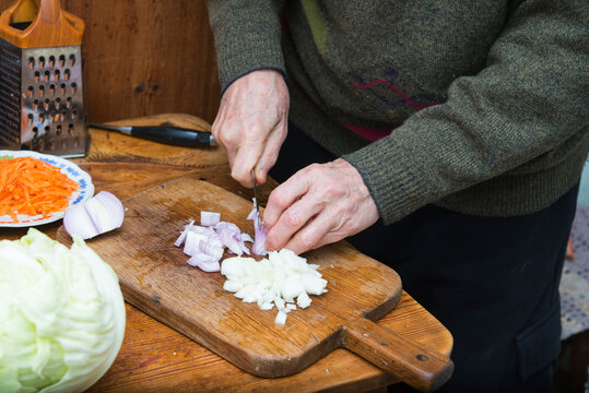 real cooking at home: man chopping onion with knife for golubtsi, traditional russian cabbage rolls