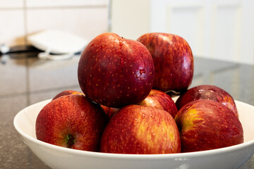 Close up of wet red apples piled in a white plate