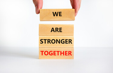 We are stronger together symbol. Concept words We are stronger together on wooden blocks. Businessman hand. Beautiful white background, copy space. Business and we are stronger together concept. - obrazy, fototapety, plakaty