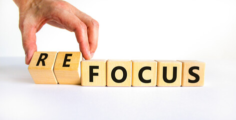 Focus or refocus symbol. Businessman turns wooden cubes and changes the word focus to refocus....