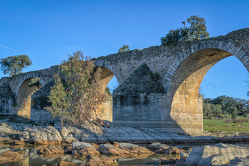 Fototapeta na wymiar Old stone bridge with arches across the river