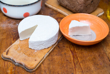 head of goat cheese on board and piece in bowl