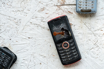 An unusual background of broken phones nailed to the wall. Old broken phones on display in a mobile...