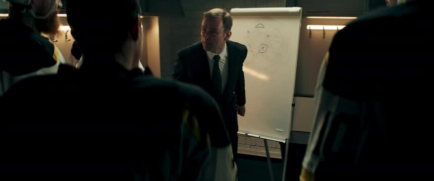 Angry disappointed coach yelling on players of ice hockey team in the locker room during the intermission. Shoot with 2x anamorphic lens
