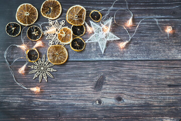 Dried orange slices, thread stars, cut snowflakes, garland on a wooden table. Place for your text. Shooting from above. Copy space