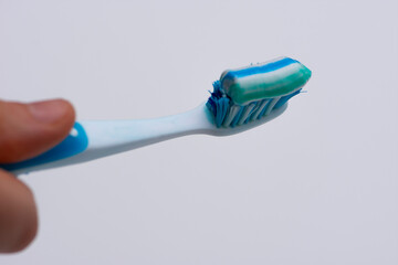 Close up of white and blue toothbrush with toothpaste on it isolated on white
