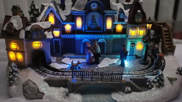 a toy model of a New Year's house in the snow and a steam locomotive riding on the rails