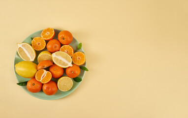 Plate of fresh juicy fruits tangerines and lemons on a yellow background. Vitamins and minerals,...