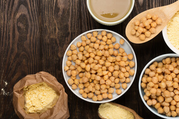 Cooked Chickpeas, aquafaba, chickpea flour on dark wooden background.