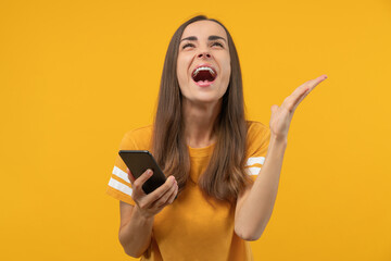 Amazed young woman with phone in hands celebrating victory in online casino, hitting jackpot in...