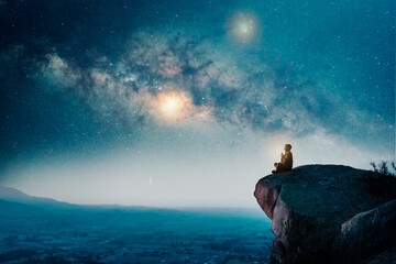 person sitting on the top of the mountain meditating or contemplating the starry night with Milky...