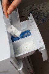 Close up of female hand pouring washing powder detergent into washing machine