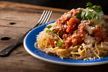 plato de spaguettis con salsa de tomate y queso rallado sobre mesa de madera rústica