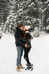 Fototapeta na wymiar Loving couple cuddling on a winter walk. Young family having fun in the frosty forest. Romantic date in winter time. Winter lovestory