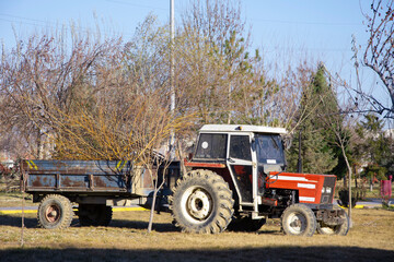 Tractor with trailer filled with old branches parked in the park