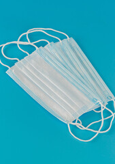 Four new medical surgical facial three-layer masks lie side by side on blue background
