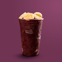 Brazilian Frozen Açai Berry Ice Cream Smoothie in plastic cup with Bananas. isolated on purple background. Front view for menu and social media