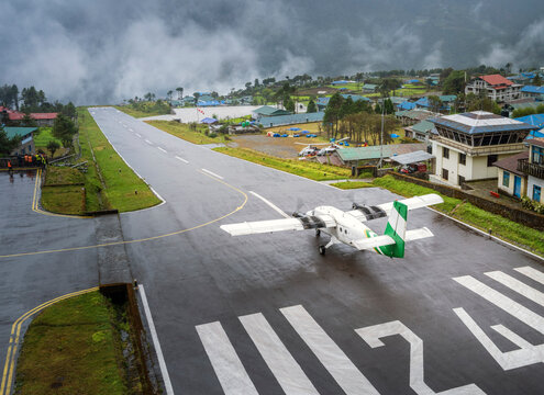 little airplane of local airlines of Nepal on the shortest runway in small airport in village Lukla before take off