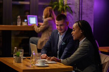Two business people having a meeting in a cafe while using a laptop