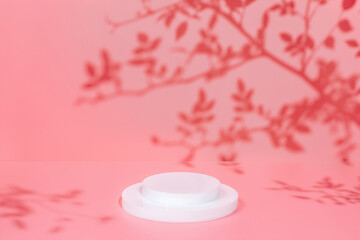 Abstract minimal nature scene - empty stage and circle podium on pink background and soft shadows of rose flowers and leaves. Pedestal for cosmetic product and packaging mockups display presentation