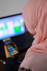 Muslim female student using laptop and mobile phone