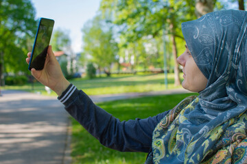 Muslim pregnant woman taking selfie in the park with smartphone