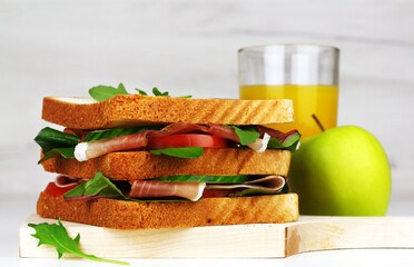 Club sandwich with spanish hamon or italian proscuitto, juice and an apple