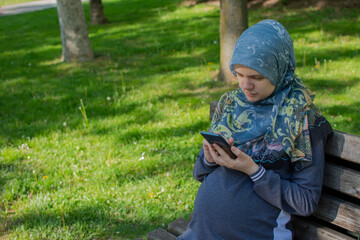Muslim pregnant woman using smartphone in the park