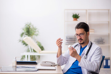 Young male doctor suggesting pills in the clinic