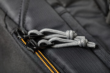 The material of the textile accessories is black. Metal zipper closure with gray strings close-up...