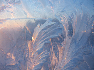Ice pattern and sunlight closeup on window glass early in the morning