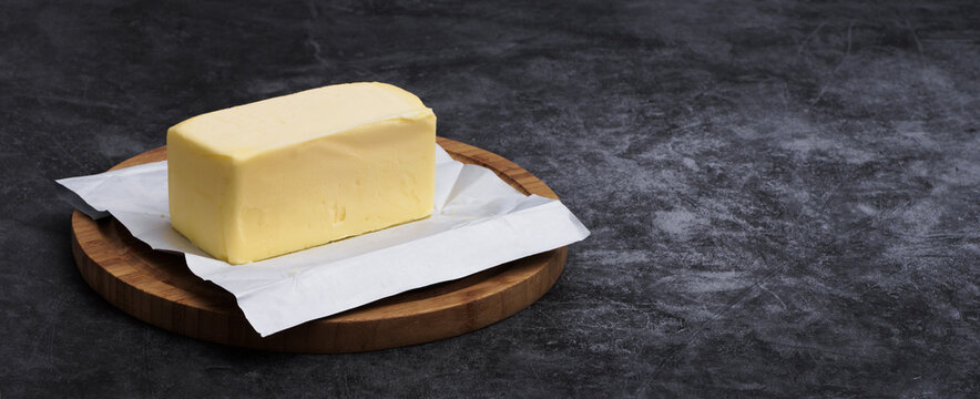 Freshly unwrapped block of butter on cutting board with copy space