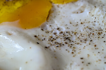 closeup of a fried egg cooked with salt and pepper