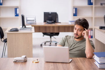 Young male employee sitting at workplace