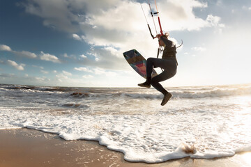 Professional kite surfer jump on sunset beach