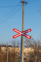 A road sign mounted on a pole indicates a railway crossing.