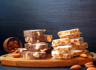 Traditional Christmas and New Year sweets. Spanish turron with almonds, wood board, almonds on dark...