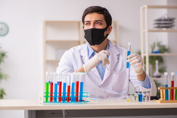 Young male chemist working at the lab during pandemic