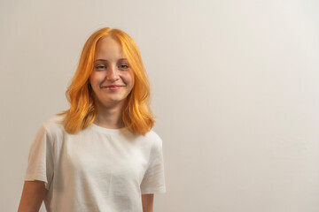 portrait of a teenage girl with red hair in a white T-shirt on a light background